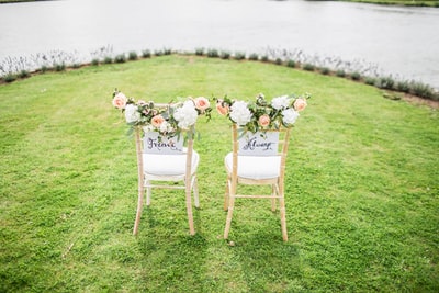 两张装饰性的椅子放在靠近水体的草地上